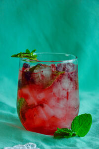 Refreshing haskap mojito cocktail garnished with mint and haskap berries