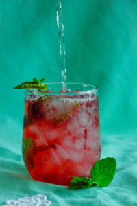 Haskap mojito being topped off with club soda, with bubbles rising in the glass.