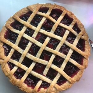 Whole haskap apple pie with a golden crust, filled with tart berries from Bokey Bloom Farms.” Keep it concise, descriptive, and focused on the content.