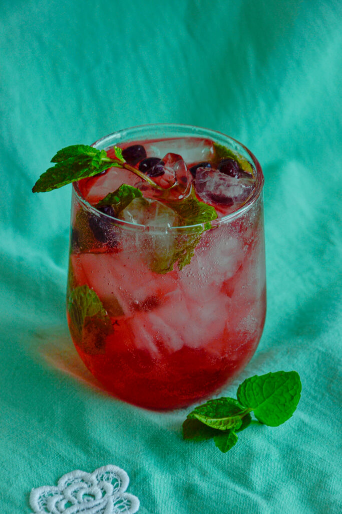 A completed haskap mojito with bubbles rising, garnished with fresh mint leaves.