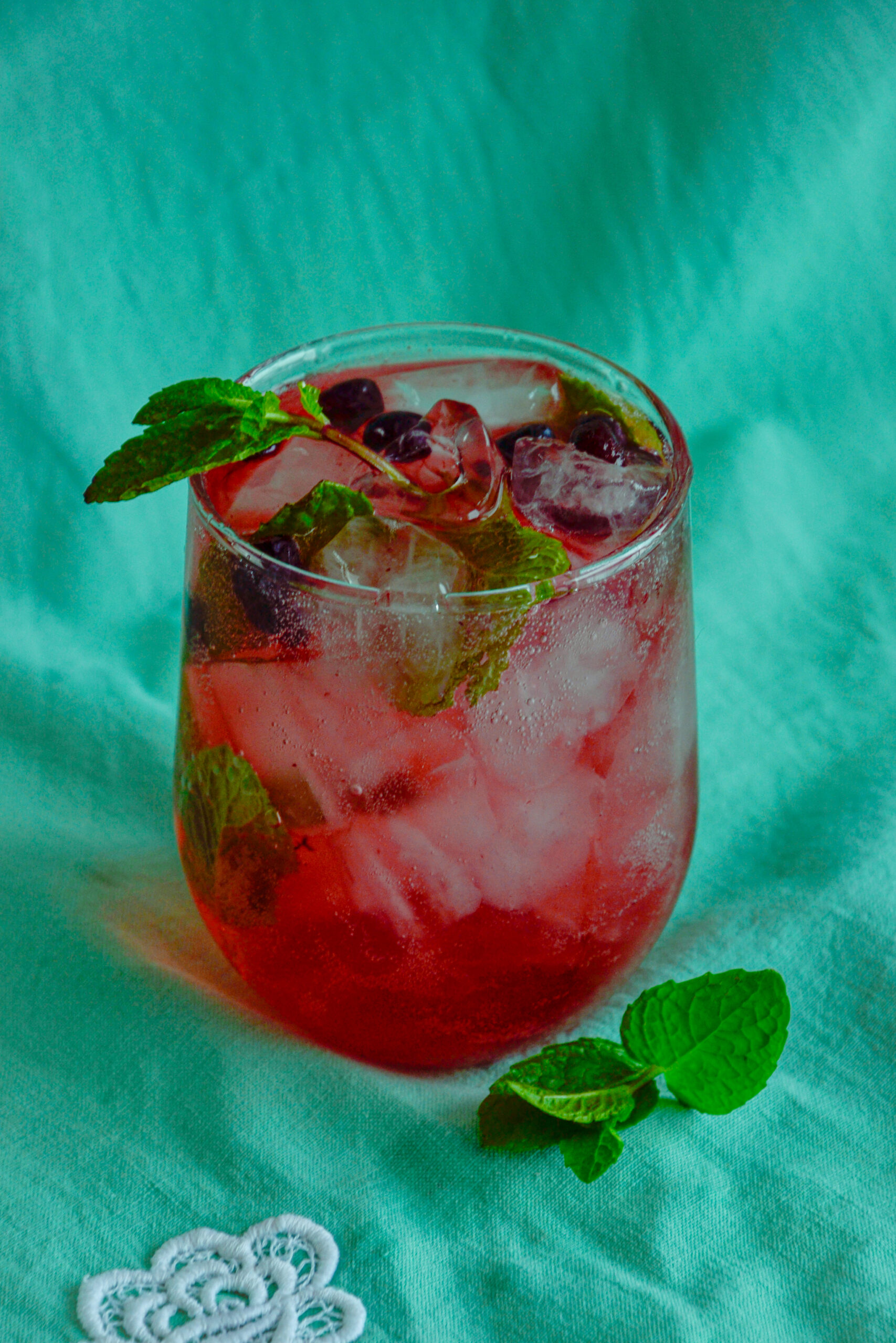 A completed haskap mojito with bubbles rising, garnished with fresh mint leaves.
